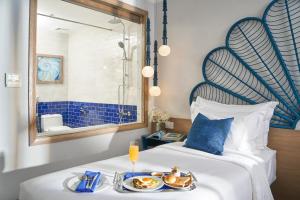 a hotel room with a bed with a tray of food at Sofiana My Khe Hotel & Spa- Rooftop Pool Bar in Danang