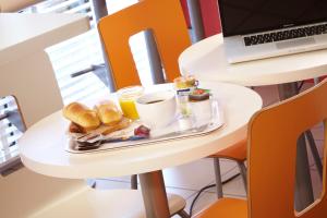 uma bandeja de comida de pequeno-almoço numa mesa com um computador portátil em Premiere Classe Boissy St Leger em Boissy-Saint-Léger