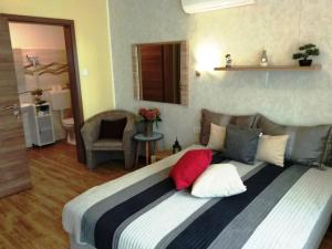 a bedroom with a large bed with red and white pillows at Tulipán Apartmanház in Bük