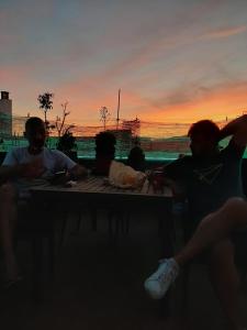 Due uomini seduti a un tavolo con il tramonto sullo sfondo di La Pita Guesthouse a Almería