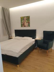 a bedroom with a bed and a blue chair at Smaragdo apartamentai in Kaunas