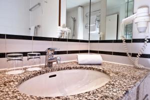 ein Bad mit einem Waschbecken und einem Spiegel in der Unterkunft Wyndham Garden Hennigsdorf Berlin in Hennigsdorf