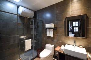 La salle de bains est pourvue de toilettes, d'un lavabo et d'un miroir. dans l'établissement Elsewhere Hotel Leifu Branch Pingyao, à Pingyao
