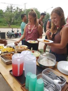 un gruppo di persone che si trovano intorno a un tavolo con cibo di Best Stay Hostel At Lanta a Ko Lanta