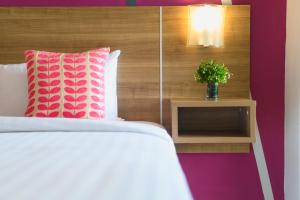 洛坤的住宿－Eco Inn Lite Nakhon Si Thammarat，一张带粉色和白色枕头的床和一张桌子