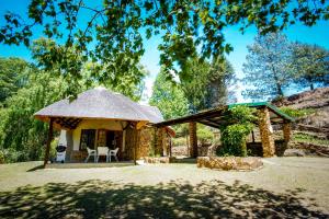 a gazebo with a thatched roof in a yard at Meadow Lane Country Cottages in Underberg
