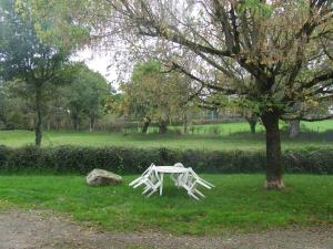 a white table sitting in the grass next to a tree at Gite à la ferme Les places in La Chapelle-Bertrand