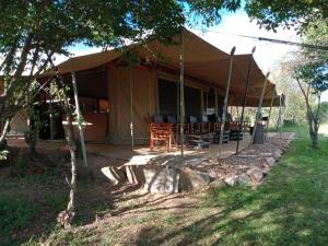 Mara Ngenche Safari Camp - Maasai Mara National Reserve في تاليك: خيمة فيها طاولة وكراسي