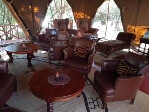 a living room with couches and chairs in a tent at Mara Ngenche Safari Camp - Maasai Mara National Reserve in Talek