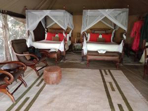 a room with two beds and chairs in a tent at Mara Ngenche Safari Camp - Maasai Mara National Reserve in Talek