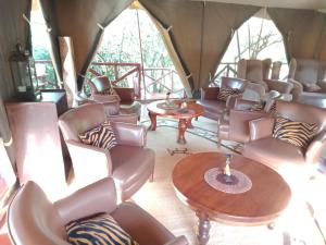 a room with chairs and tables in a tent at Mara Ngenche Safari Camp - Maasai Mara National Reserve in Talek