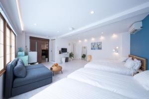 a bedroom with two beds and a blue couch at STAY ARI Arakicho in Tokyo