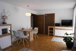ein Wohnzimmer mit einem Tisch, Stühlen und einem TV in der Unterkunft Ferienwohungen Wassertheurer in Sankt Kanzian am Klopeiner See