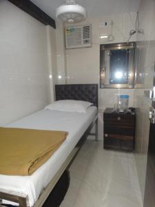 Hotel Qamar في مومباي: غرفة نوم صغيرة مع سرير وموقف ليلي