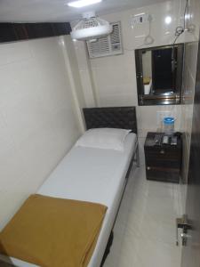 Hotel Qamar في مومباي: غرفة نوم صغيرة مع سرير ومرآة