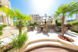 a patio with tables and chairs and palm trees at Harmony Suites Saint Vlas in Sveti Vlas