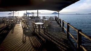 a wooden deck with tables and chairs on the water at Sol Victoria Marina Lofts in Salvador