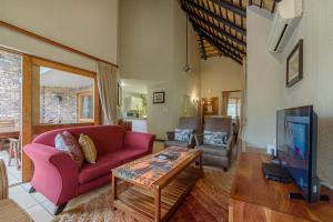een woonkamer met een roze bank en een tv bij Kruger Park Lodge Unit No. 524 in Hazyview