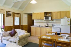 a living room with a couch and a table in a kitchen at shady brook cottages in Harrietville