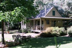 a house with chairs and a table in front of it at shady brook cottages in Harrietville