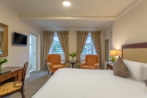 um quarto de hotel com uma cama, uma secretária e cadeiras em Dooley's Hotel em Waterford