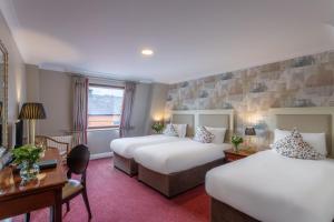 a hotel room with two beds and a desk at Dooley's Hotel in Waterford