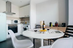 a white kitchen with a white table and chairs at HOMEABOUT RETIRO Apartment II in Madrid