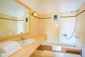 bagno con lavandino, vasca e specchio di Maganos Apartments a Paraga