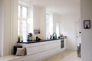 una cocina con armarios blancos y encimeras negras en ApartmentInCopenhagen Apartment 1357, en Copenhague