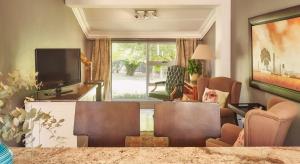 a living room with a table and chairs and a television at Upper House Guesthouse in Clarens