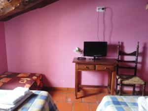 a bedroom with a desk with a tv and a bed at Hostal Venta Liara in Allepuz