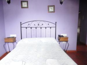 a bed room with a white bedspread and a wooden headboard at Hostal Venta Liara in Allepuz