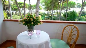 une table avec un vase de fleurs et deux verres dans l'établissement Villa Scultura Seaview, à Lignano Sabbiadoro