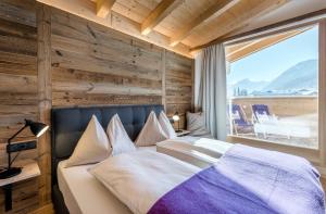 um quarto com uma cama e uma grande janela em Almdorf Almlust em Flachau