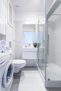 a white bathroom with a toilet and a washing machine at Malibu - Gdynia Świętojańska Centrum - Praia Apartments in Gdynia