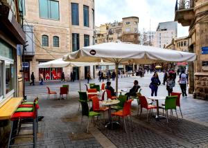 um café ao ar livre com mesas e cadeiras e um guarda-sol em The boutique em Jerusalém