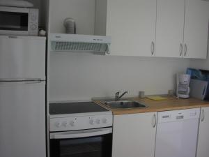 a kitchen with a stove, refrigerator, microwave and sink at Strandvejen Apartment in Skagen