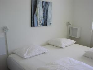 2 almohadas blancas en una cama con un cuadro en la pared en Plesners Anneks, en Skagen