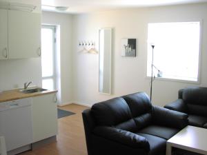 sala de estar con sofá de cuero negro y cocina en Plesners Anneks, en Skagen