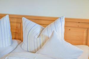 a bed with white pillows on top of it at Jaudenhof - Apartment Schönbergalm in Lenggries
