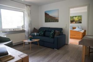 sala de estar con sofá azul y cama en Winzerhof Düring en Iphofen