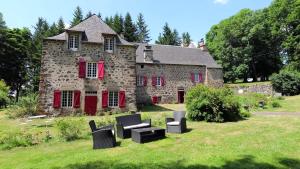 an old stone house with black furniture in front of it at Ferme des Prades in Landeyrat