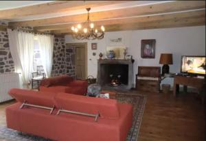 a living room with a red couch and a fireplace at Ferme des Prades in Landeyrat