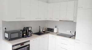 a white kitchen with white cabinets and a microwave at Apartament Fibra Essenza in Rybnik