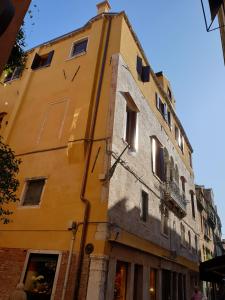 ein gelbes Gebäude mit einer Uhr auf der Seite in der Unterkunft Ca' dei Proverbi Suites in Venedig