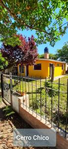 uma cerca em frente a uma casa amarela em Cerro Chico em Villa Cura Brochero