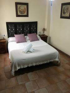 1 dormitorio con 1 cama blanca grande con almohadas moradas en El Balcón del Albaicín, en Granada