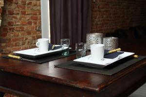 デンデルモンデにあるB&B Casa Luna Loftの白皿2枚とメガネが掛けられたテーブル