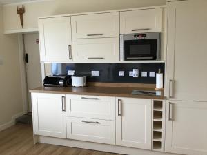 a kitchen with white cabinets and a microwave at Valtos 23 Isle of Lewis in Uig