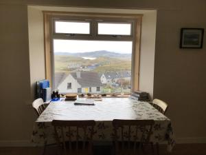 a dining room table with a view of a house at Valtos 23 Isle of Lewis in Uig